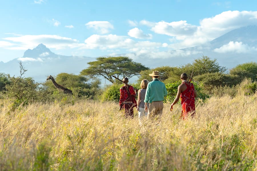 A guided walk with Maasai guides, a giraffe, and Kilimanjaro behind